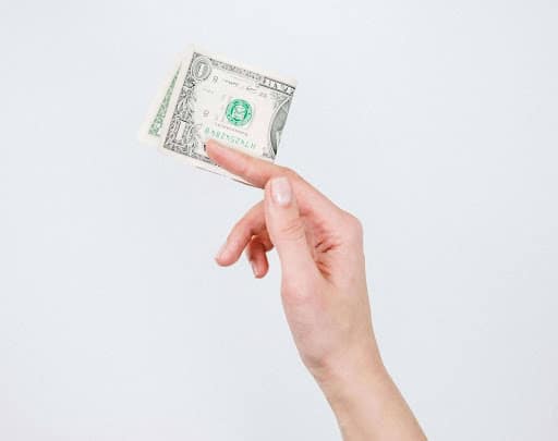 Hand holding money, indicating financial settlements in the context of fire damage claims.